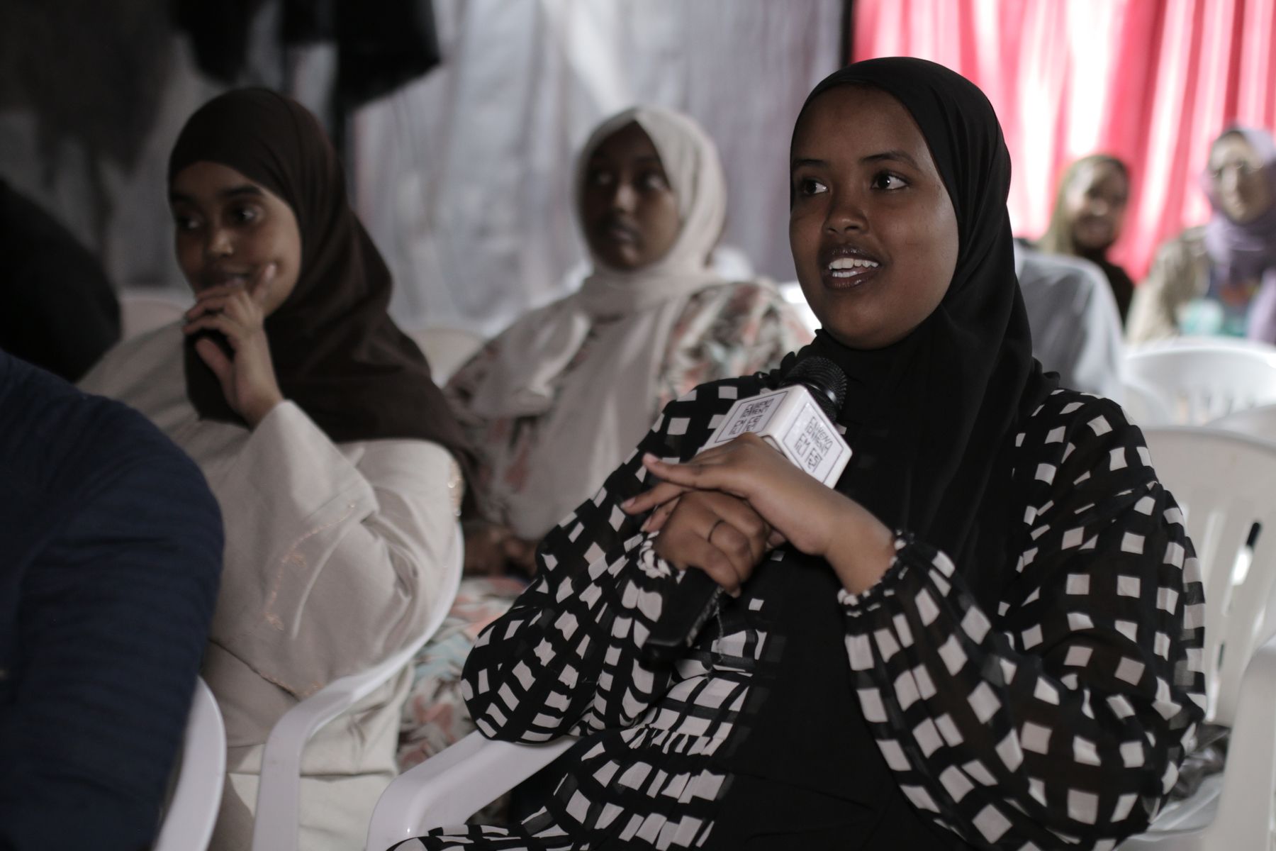 A young woman in the audience speaks into the microphone
