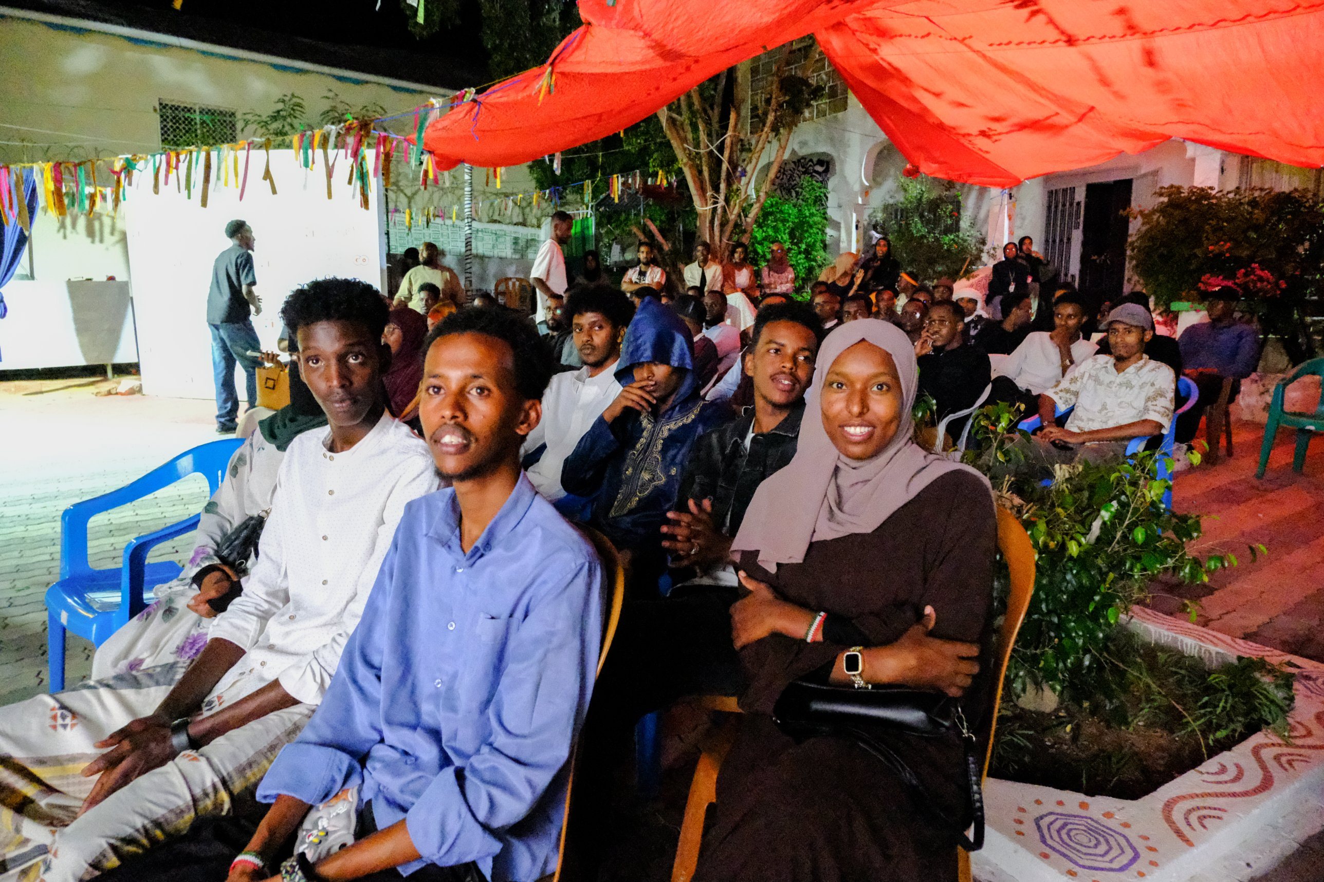 Smiling guests in the front row of the audience under the red canopy